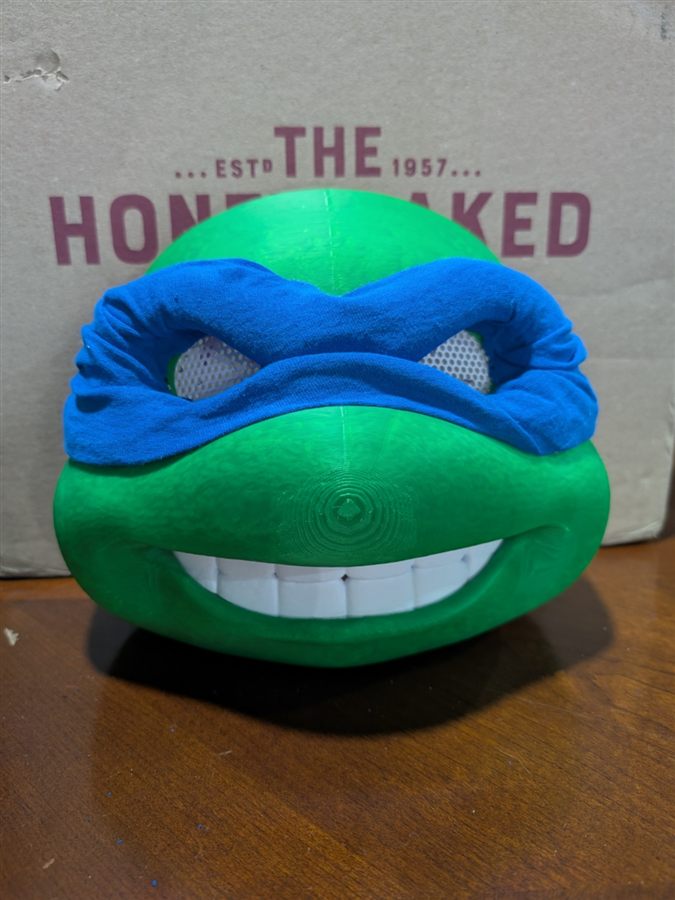 Green 3D-printed Leonardo from the Teenage Mutant Ninja Turtles with a blue cloth bandana, white teeth, and mesh in the eye openings